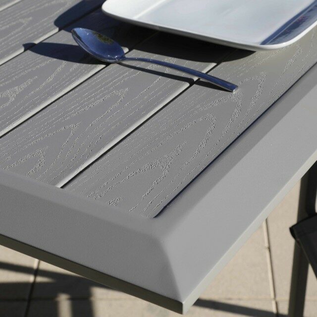 L'image présente une superbe table en aluminium de la gamme Arano, affichant un design moderne et élégant. La surface de la table est parfaitement lisse, reflétant la lumière ambiante de manière subtile.