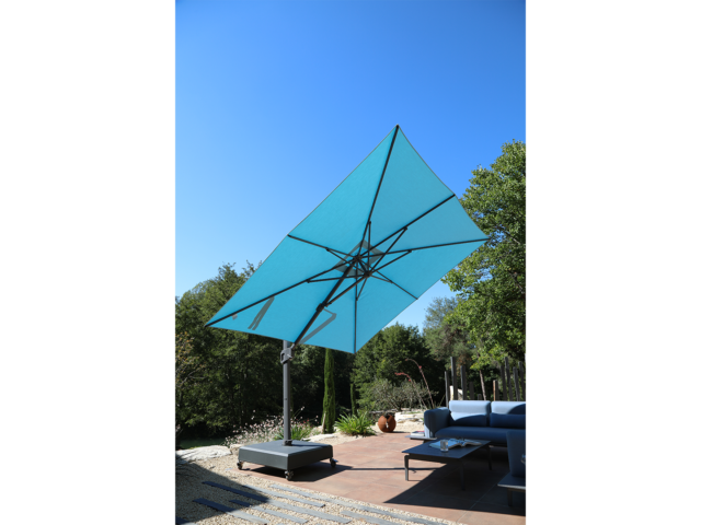 Parasol déporté - Centaurus Bleu Minéral. Parasol Premium anti-UV – Bleu (3.5×3.5) la structure est renforcée avec un mât 75x100mm et 2.2mm d’épaisseur. Cette structure “super strong” permet suivant les calculs du département R&D une inclinaison de seulement 3°. C’est un parasol déporté et anti-UV.