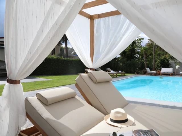 Détail du rideau entourant le lit double de piscine à baldaquin en Teck avec coussin polyester.